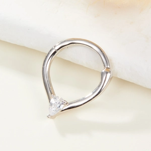 Vue macro d'un anneau de nez en argent avec zircon poire sur une surface en pierre blanche