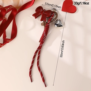Detail of red bow keychain with bear charm, heart pendant, and precise size dimensions