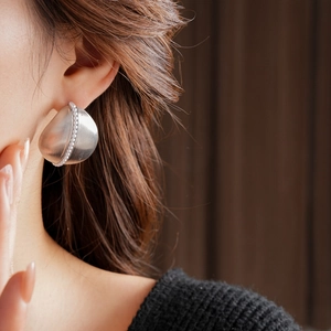 Macro detail of silver drop pearl earring with brushed metal texture on a model's ear