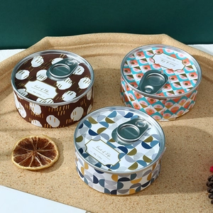 Top view of three 80g tinplate scented candles with decorative patterns on a cork tray