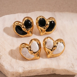 Macro shot of black and marbled white enamel heart earrings on a stone display