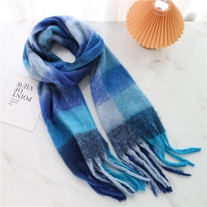 Detail of blue gradient plaid scarf with long tassels on a marble surface