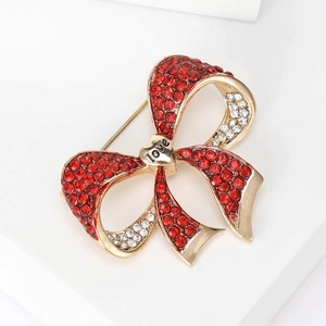 Close-up of red rhinestone bow brooch with heart-shaped Love engraving in gold