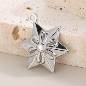 Gros plan d'un pendentif étoile argenté avec motif floral sur une surface en pierre