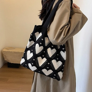 Close-up of heart pattern knit tote bag worn by a model in a natural indoor setting