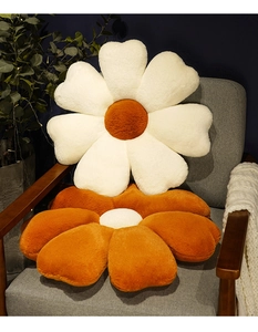 Close-up of flower shaped plush cushions in orange and white on a grey armchair