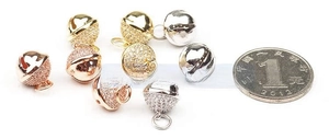 Macro detail of micro-paved zircon bell charms in gold, silver and rose gold for DIY jewelry