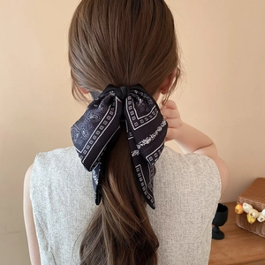 Elegant black bow hair clip with white paisley print on brown hair in a French style