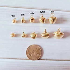 Golden metal bells in five sizes from 6mm to 14mm compared with a coin on white wood