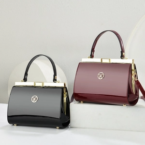 Detail view of glossy snake skin pattern clutches in black and burgundy with gold hardware