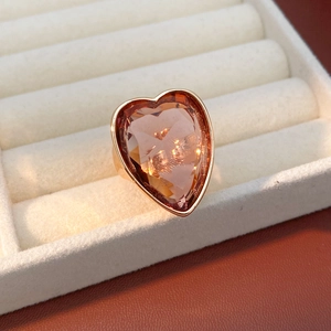 Close-up of oversized peach zircon heart ring on white velvet jewelry display tray