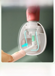 Close-up of wall-mounted toothpaste dispenser showing precise squeeze action on toothbrush
