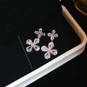 Macro detail of silver-tone snowflake earrings with sparkling cubic zirconia on black velvet