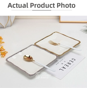 Detailed view of white ceramic square plates with gold and silver beaded edges and cutlery