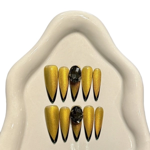 Golden cat eye press-on nails with black French tips and rhinestone accents