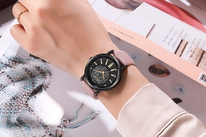 Détail de la montre femme au cadran étoilé avec aiguilles or rose et bracelet en daim rose