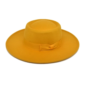 Detail of a bright yellow wool fedora hat featuring a matching grosgrain ribbon bow