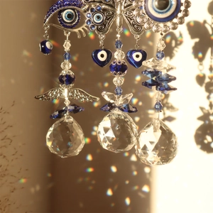 Macro shot of evil eye crystal suncatcher with rainbow reflections and silver wing detail