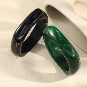 Chunky irregular resin rings in black and dark green marble finish on minimalist background