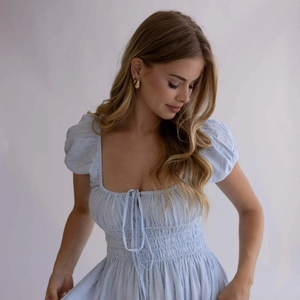 Detalle de vestido a rayas azul claro con mangas abullonadas y escote cuadrado en modelo