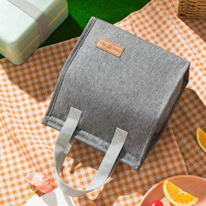 Minimalist grey insulated lunch bag with Tasty Food leather patch on picnic blanket