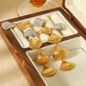 Macro view of gold and silver shell-shaped drop earrings in a wooden jewelry box