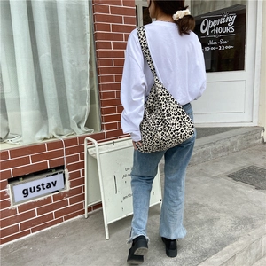 Back view of a trendy large capacity leopard print canvas tote bag on female model