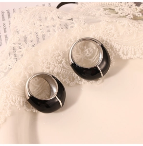 Detailed view of wide black enamel stainless steel rings on a vintage book and lace background