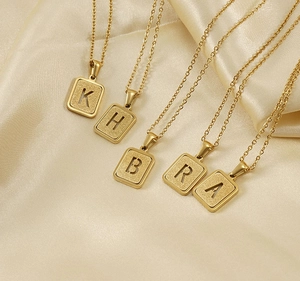 Detalle de los collares con letras bañados en oro de 18K K H B R A sobre seda dorada