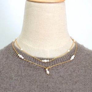 Elegant double-layered freshwater pearl necklace with golden chain on grey sweater