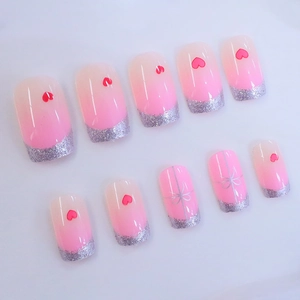 Pink gradient press-on nails with silver glitter french tips and red heart designs