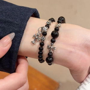 Gros plan de bracelets en perles noires avec pendentifs croix en argent sur le poignet