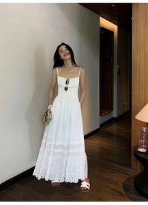 Détail d'une robe longue en coton blanc avec broderie ajourée et ourlet à plusieurs niveaux