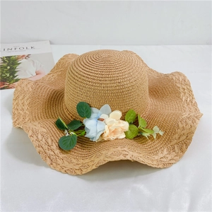 Detail of hand-woven straw hat with floral accents and wavy brim for sun protection