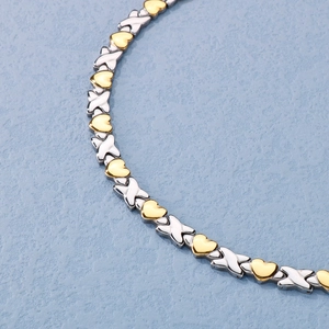 Detailed view of silver X-links and golden hearts chain in polished titanium steel