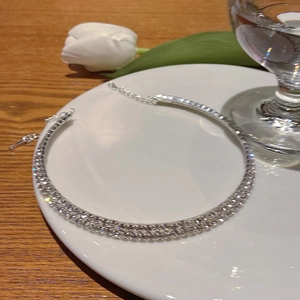 Choker argenté élégant avec cristaux pavés étincelants sur assiette déco et tulipes