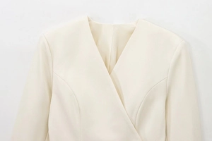 Detailed close-up of cream wrap suit featuring elegant V-neck and textured fabric