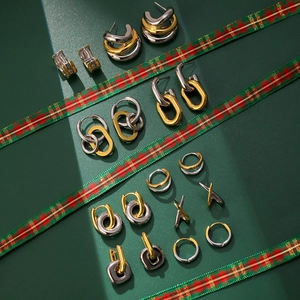 Gros plan de créoles géométriques bicolores or et argent sur cuir vert élégant