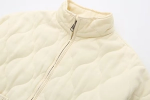 Detailed macro view of quilted collar and metal zipper on the off-white quilted jacket