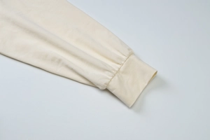 Close-up of ribbed cuffs on a minimalist cream-colored long sleeve crop top