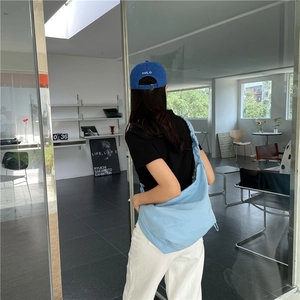 Dettaglio della borsa a tracolla in nylon azzurro con coulisse indossata da una modella