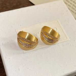 Macro view of 18K brushed gold C-shaped earrings with parallel rows of zircon inlay