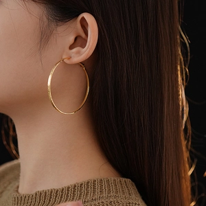 Close-up of textured gold hoop earring on model with elegant warm lighting