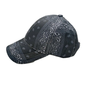 Close-up of black baseball cap featuring white paisley patterns and curved brim detail