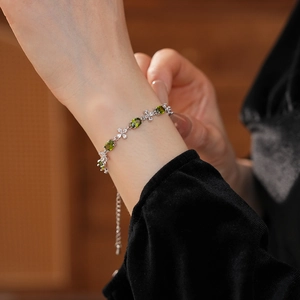 Detail of olive green flower zircon bracelet on wrist with elegant silver metal chain