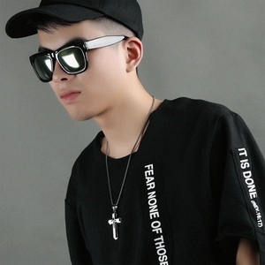 Gros plan d'un collier à triple croix argentée sur un mannequin homme avec t-shirt noir