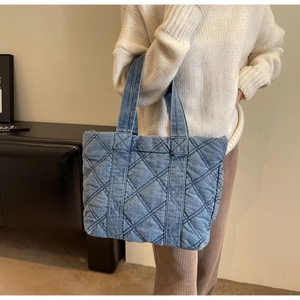 Détail du sac fourre-tout en jean bleu avec motif à carreaux matelassés et bandoulière chic