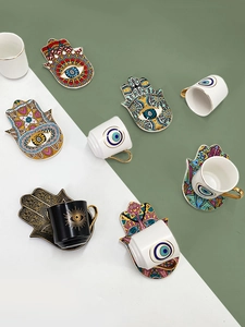 Top view of ceramic Turkish coffee cups and Hamsa hand saucers with evil eye patterns