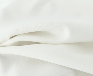 Close-up of white lace embroidery fabric texture and pleated detail on the garment