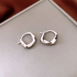 Macro shot of silver pleated oval earrings with a polished finish and minimalist design
